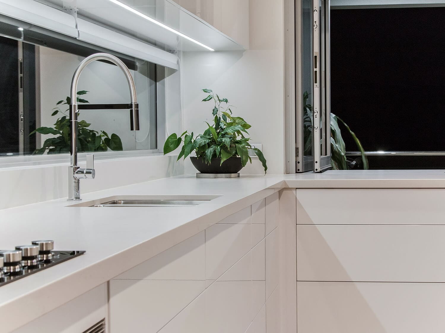 Handleless white cabinetry with a stainless steel pull-out mixer tap