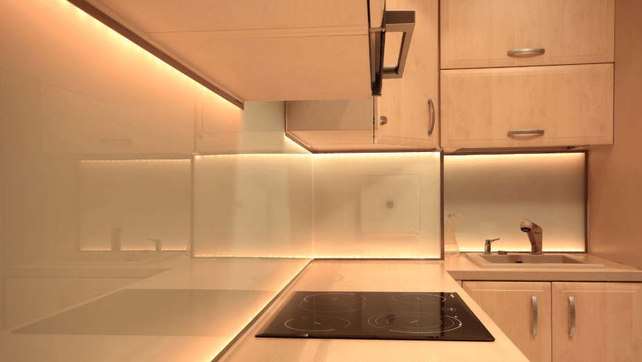 Under-cabinet LED task lighting above a cooktop in a modern kitchen