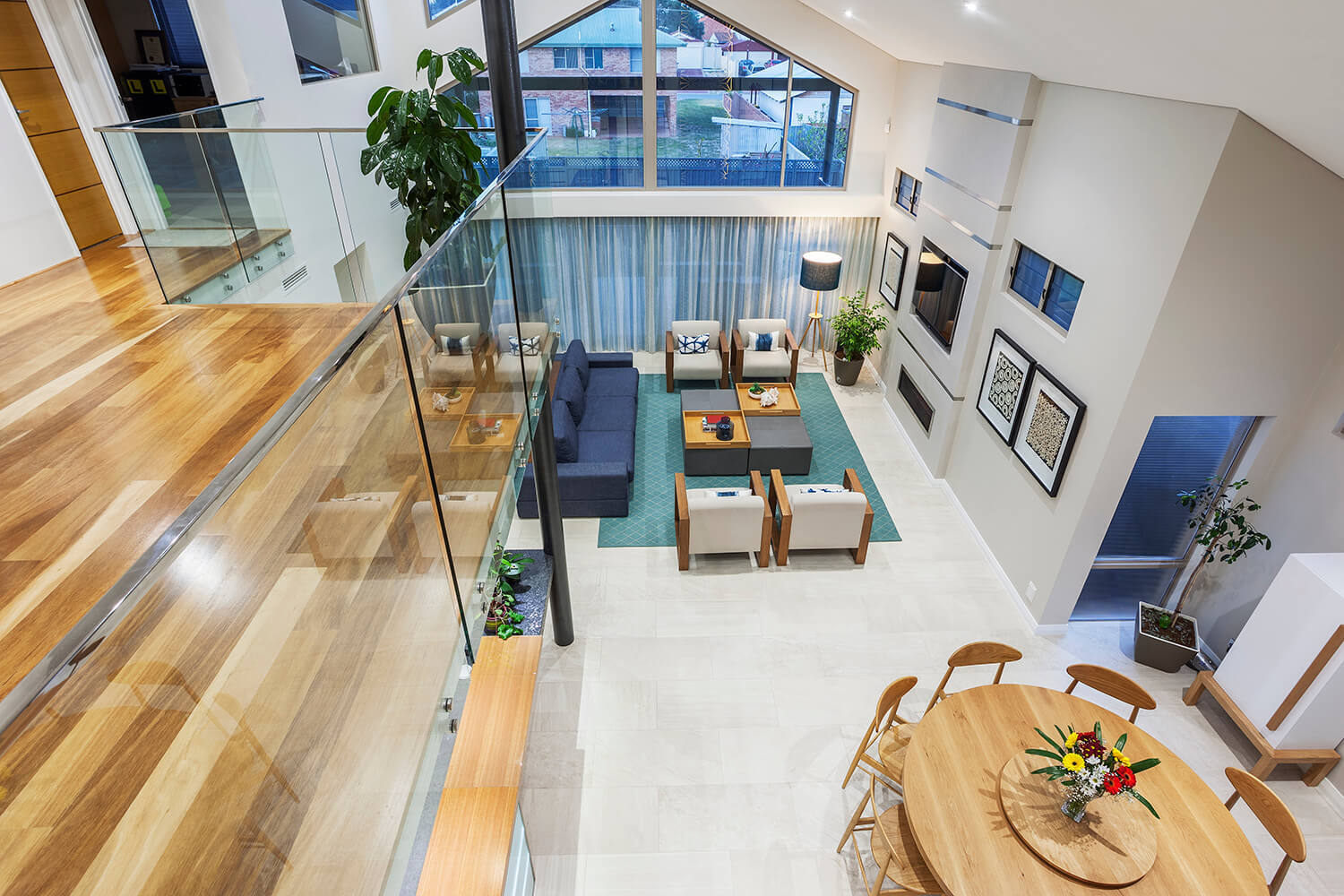 Open-plan luxury home interior with glass balustrade balcony overlooking a double-height living area