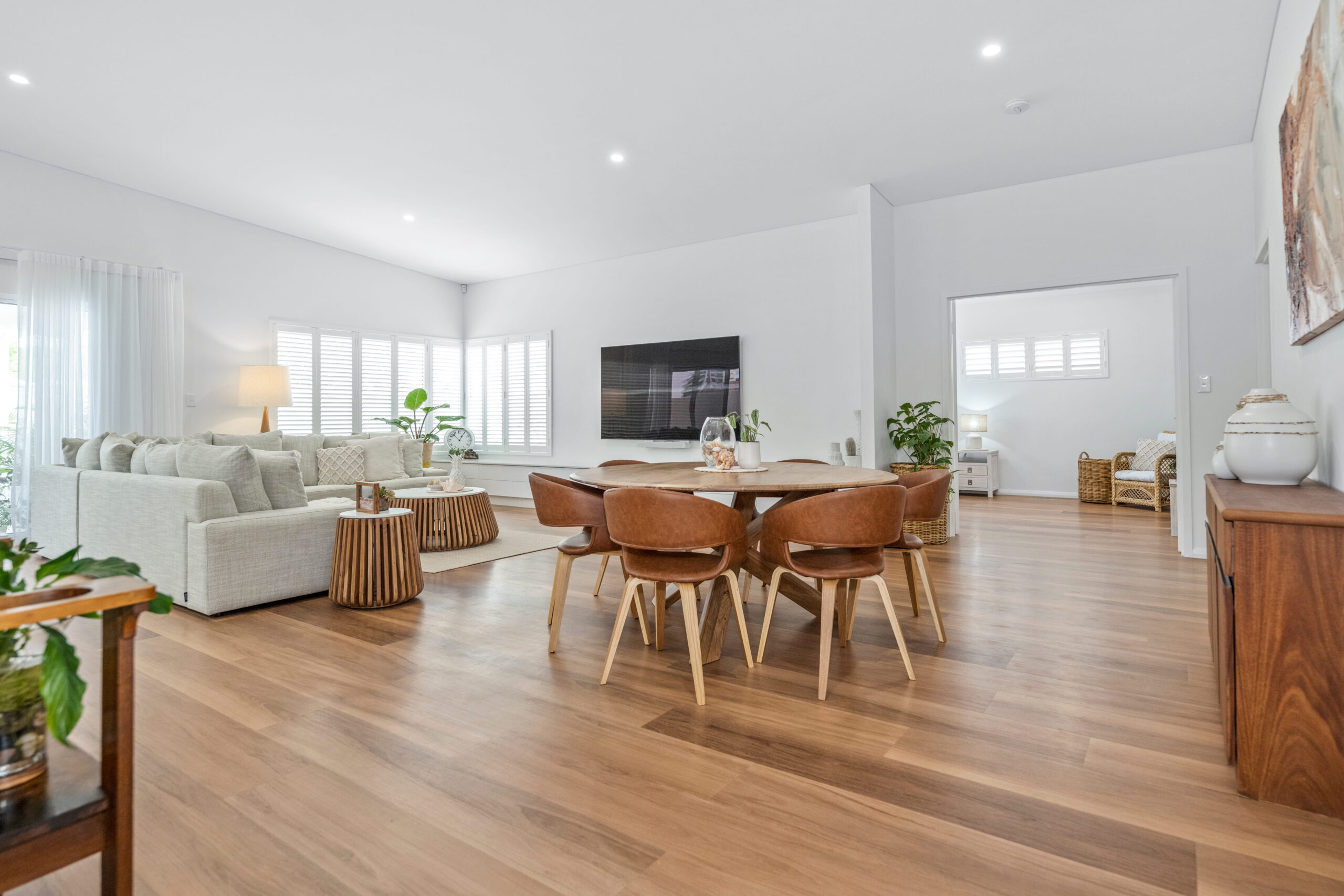 Open-plan dining and living area in a custom Makin Homes build, featuring timber flooring, plantation shutters, and high ceilings