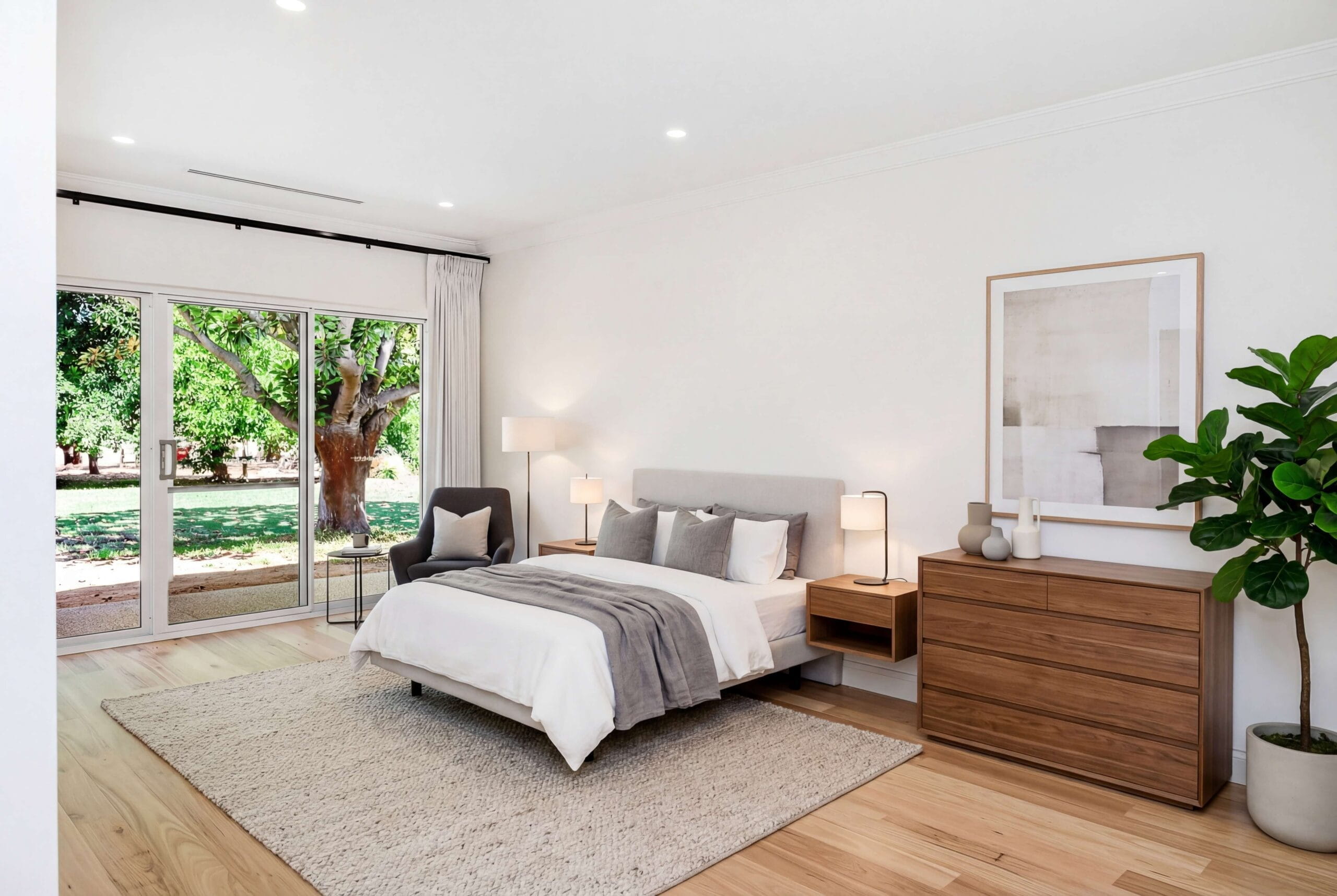 Light-filled main bedroom with timber flooring and sliding doors opening to the garden