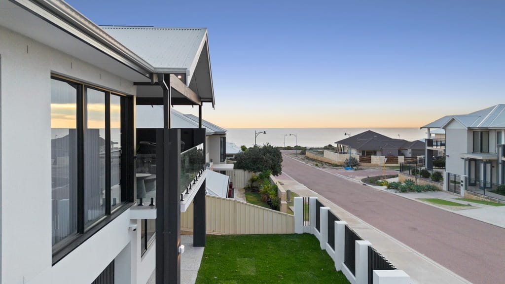 Two-storey coastal home overlooking a residential street and ocean in Mandurah